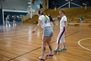 Coach Stacey (right) giving Louise (left) feedback on her technique at an indoor roller skating class.