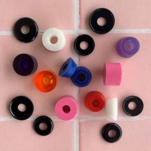 An assortment of roller skate cushion and caps on a pink and white tiled background.