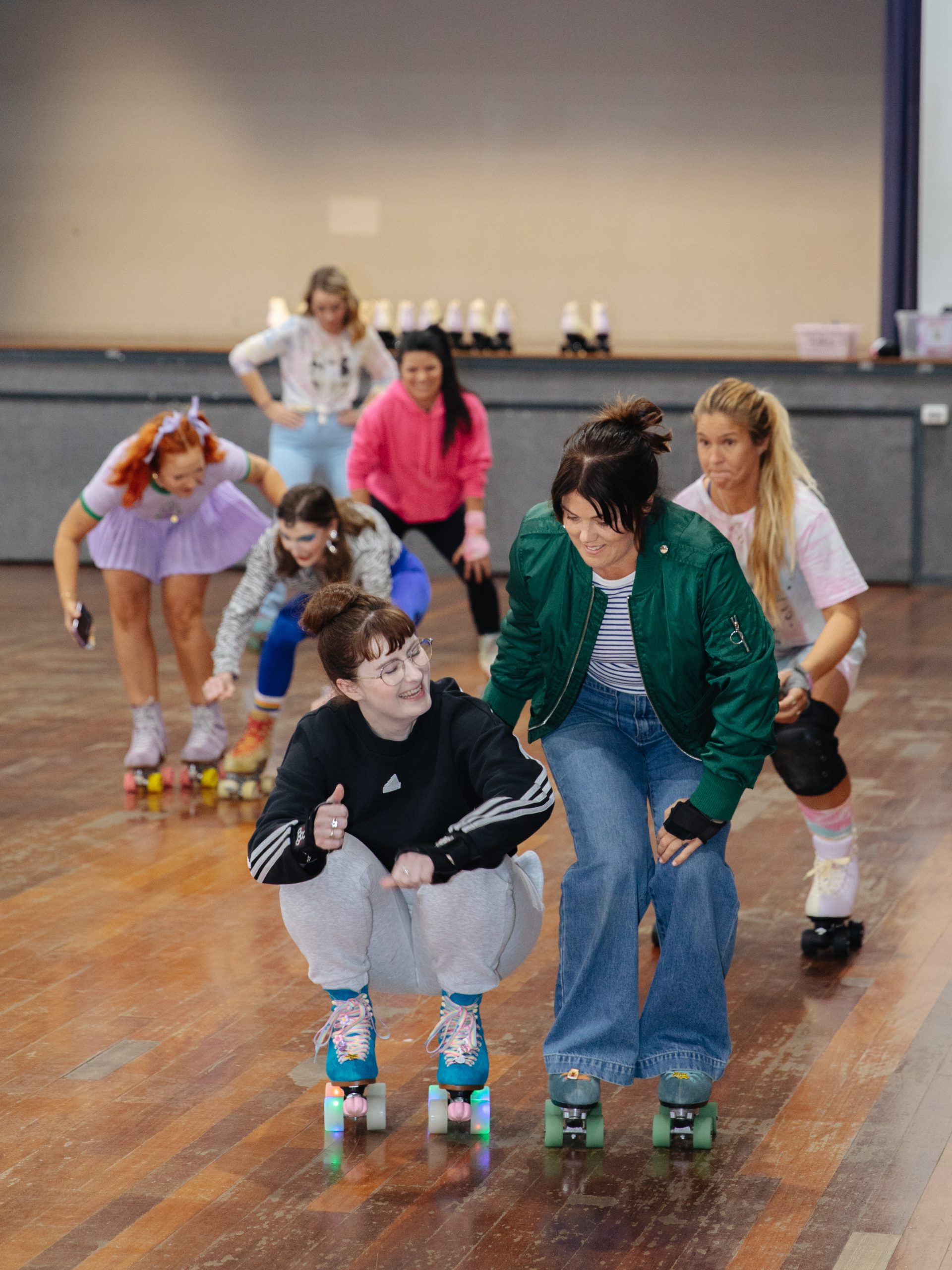 A group of 7 skaters playing a crouching game on roller skates at a RollerFit class.