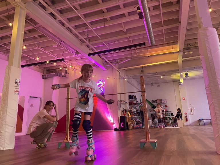 A kids party in action at RollerMart, Sydney. Kids are playing limbo on roller skates.